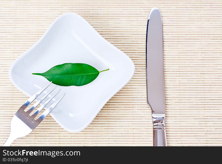 Green leaf on a plate as vegetarian diet - concept of healthy dieting