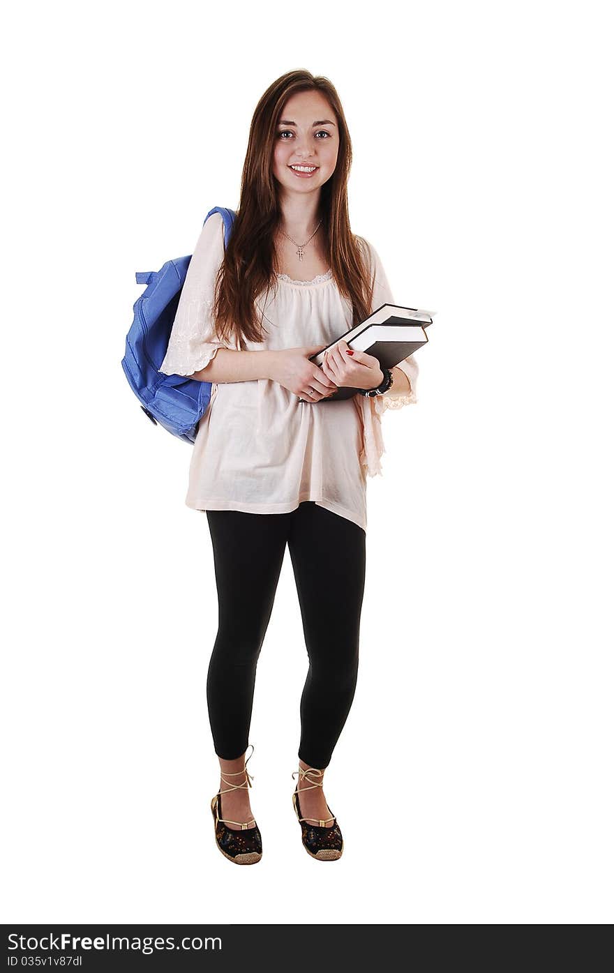 A pretty teenager in black tights and a blue backpack over her shoulder and books in her hand, standing in the studio for white background. A pretty teenager in black tights and a blue backpack over her shoulder and books in her hand, standing in the studio for white background.