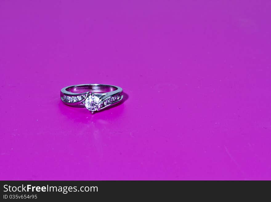 White Gold diamond engagement ring on a pink background in a studio setting. White Gold diamond engagement ring on a pink background in a studio setting