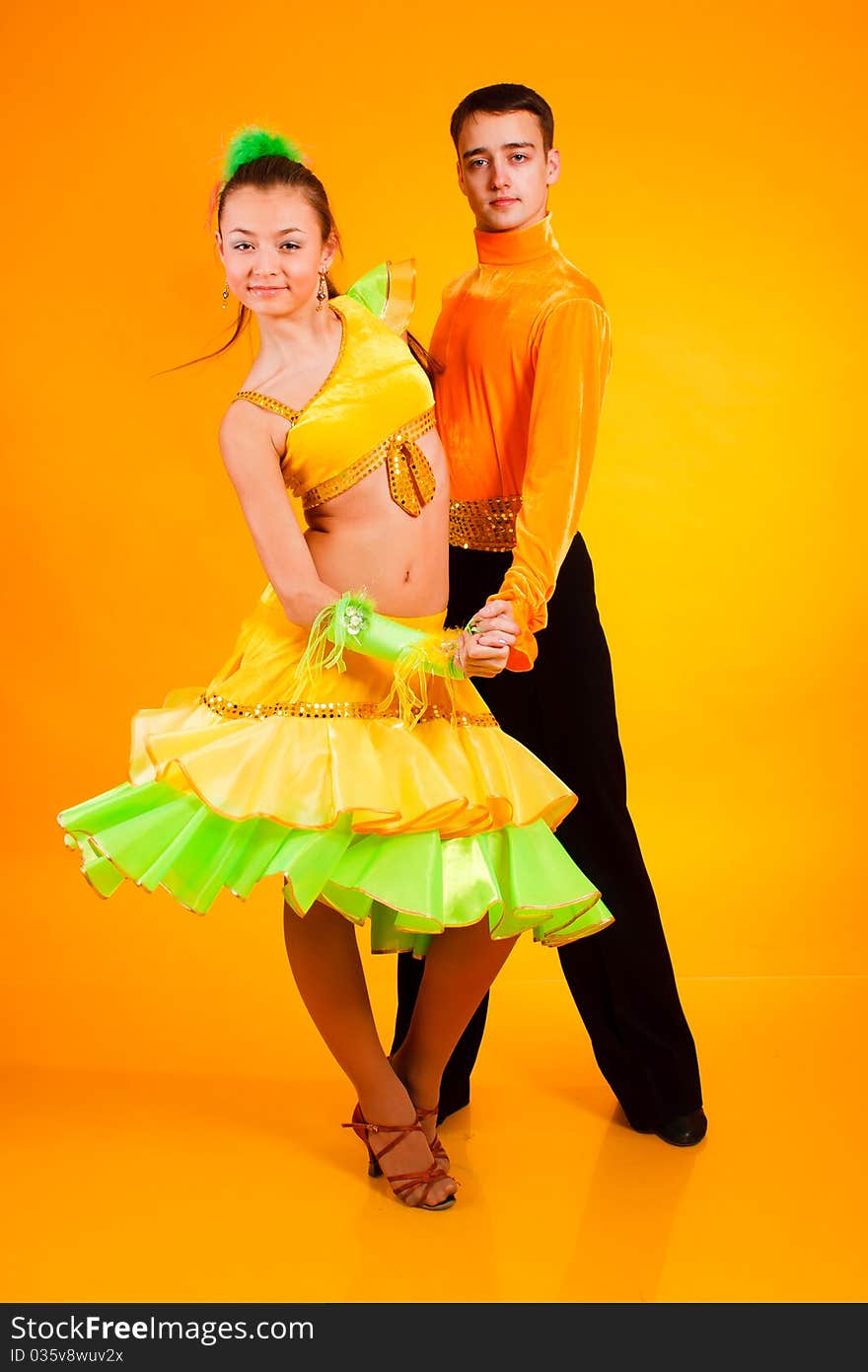 Charming young  pair in good-looking suits on a yellow background