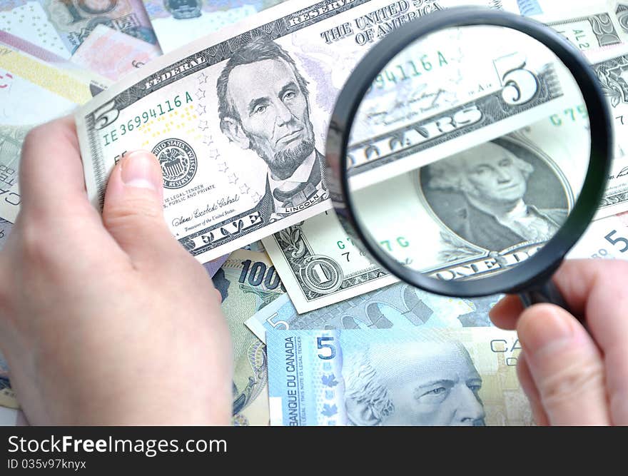 Woman checks her US five dollar bill with Magnifying glass. Woman checks her US five dollar bill with Magnifying glass