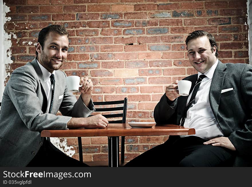 Business partners smile towards camera with coffee in hand. Business partners smile towards camera with coffee in hand