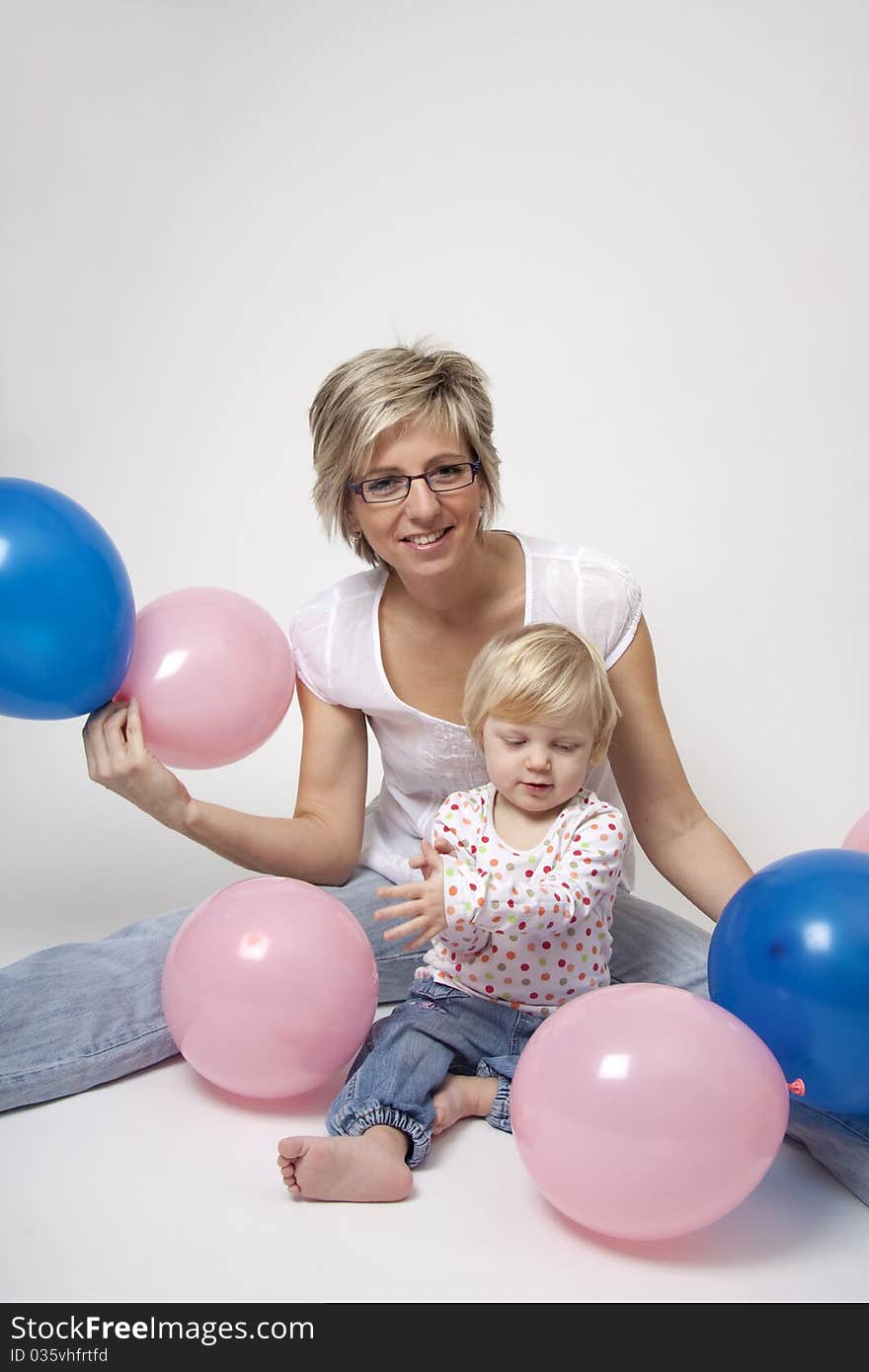 Portrait of cute girl with her mother with pink and blue balloons having fun at the party. Portrait of cute girl with her mother with pink and blue balloons having fun at the party