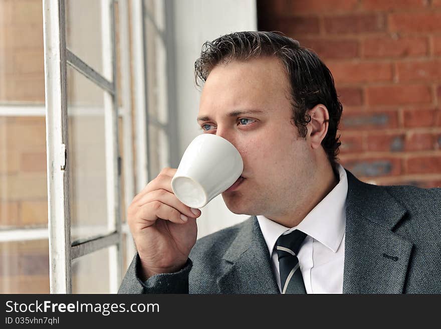 Old style man with coffee at the window while wearing suit. Old style man with coffee at the window while wearing suit