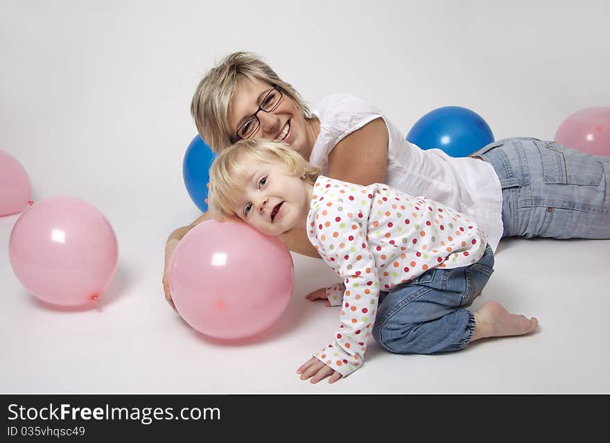 Portrait of cute girl with her mother with pink and blue balloons having fun at the party. Portrait of cute girl with her mother with pink and blue balloons having fun at the party