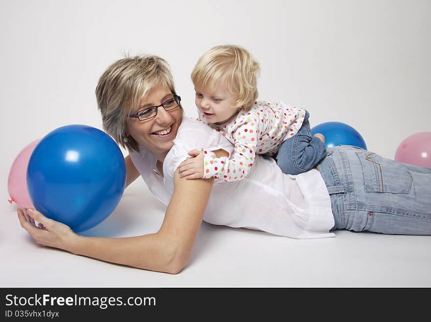 Portrait of cute girl with her mother  with pink and blue balloons having fun at the party. Portrait of cute girl with her mother  with pink and blue balloons having fun at the party