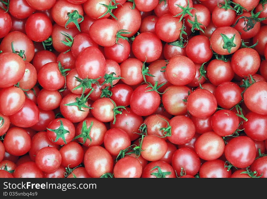 Many deep red tomatoes with green stems, full with antioxidants