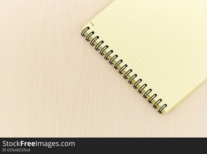 Yellow note book with lots of room for your text or image on a wooden desk