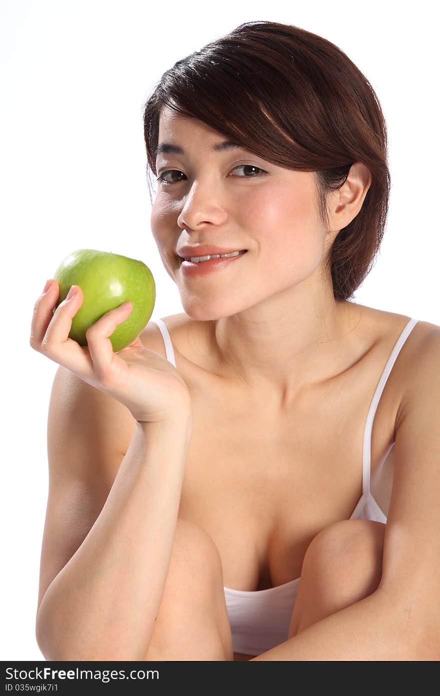 Beautiful young Japanese girl, wearing white sports underwear, sitting down holding a green apple. Model has lovely smile to camera. Beautiful young Japanese girl, wearing white sports underwear, sitting down holding a green apple. Model has lovely smile to camera.