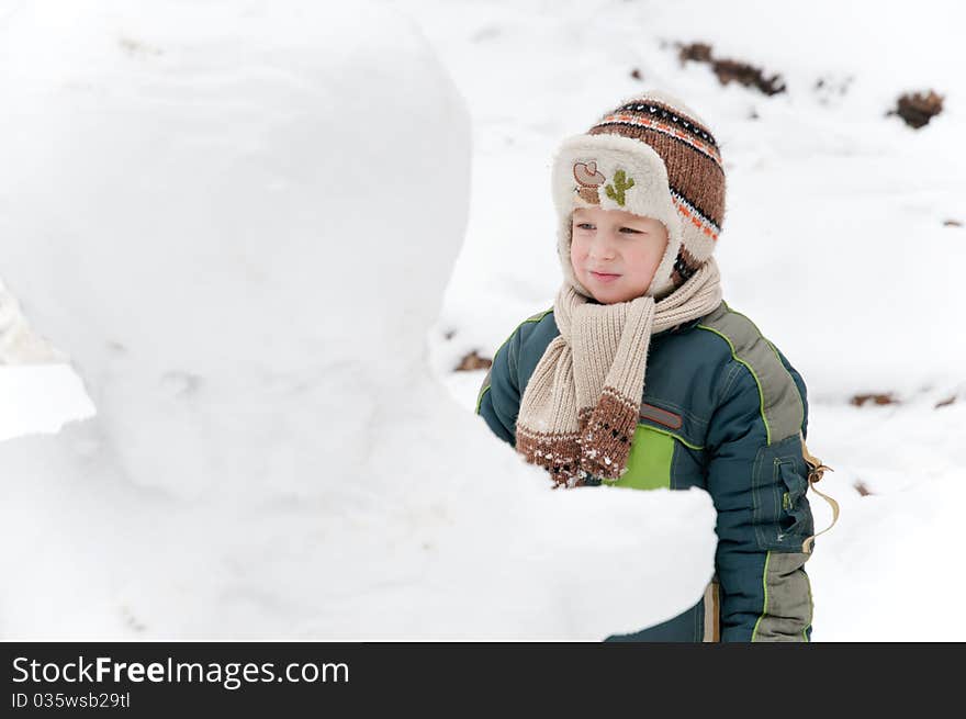 The child thoughtfully looks at the snowman. The child thoughtfully looks at the snowman