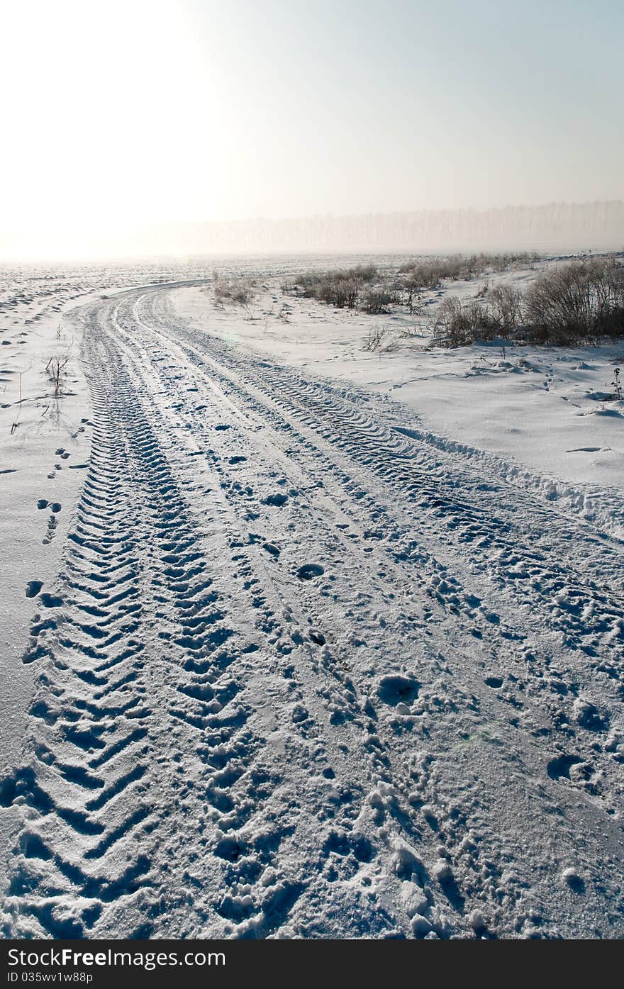 Traces of a tractor in the snow on the field road. Traces of a tractor in the snow on the field road