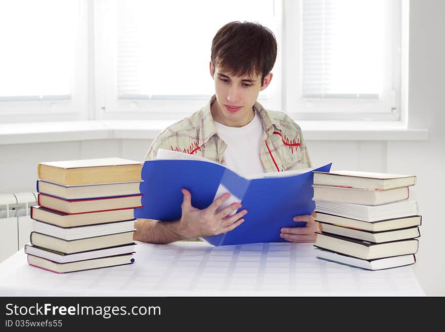 Student sits at a table and read documents. Student sits at a table and read documents