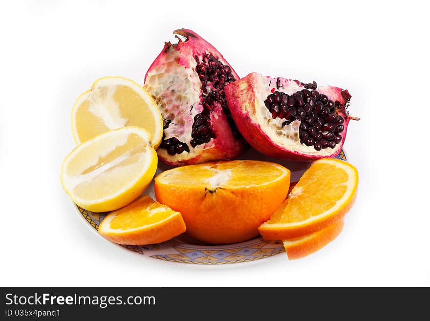 Cut pomegranate, orange and lemon on a plate isolated on white background. Cut pomegranate, orange and lemon on a plate isolated on white background