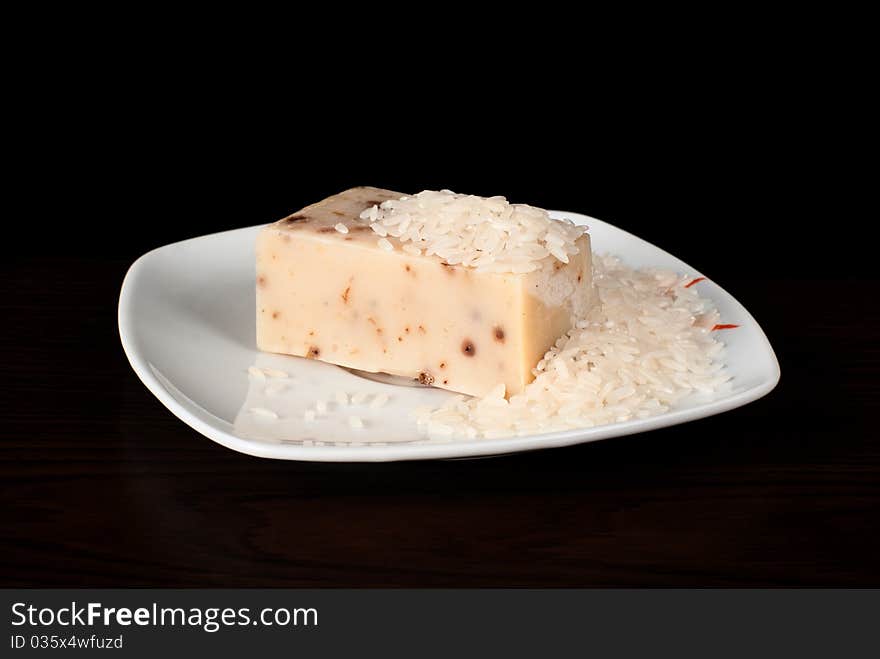 A piece of handmade soap with rice on the plate. A piece of handmade soap with rice on the plate.