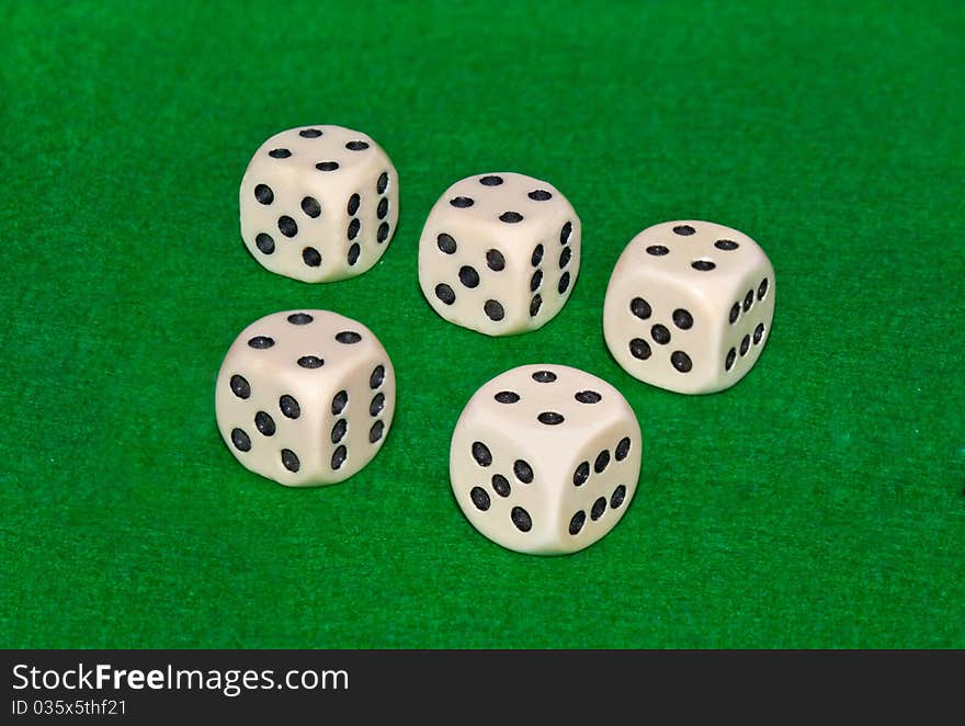 Five dices on on green casino table