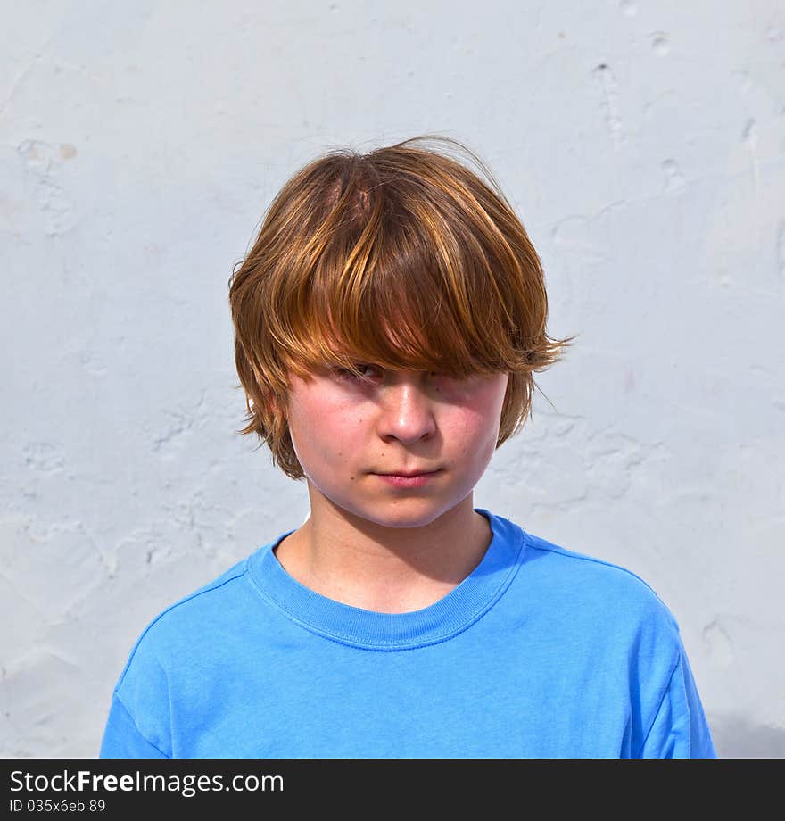 Portrait of an unhappy young boy in sunlight with white wall. Portrait of an unhappy young boy in sunlight with white wall