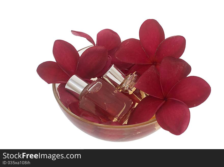 Spa concept - red plumeria and perfume bottles in bowl