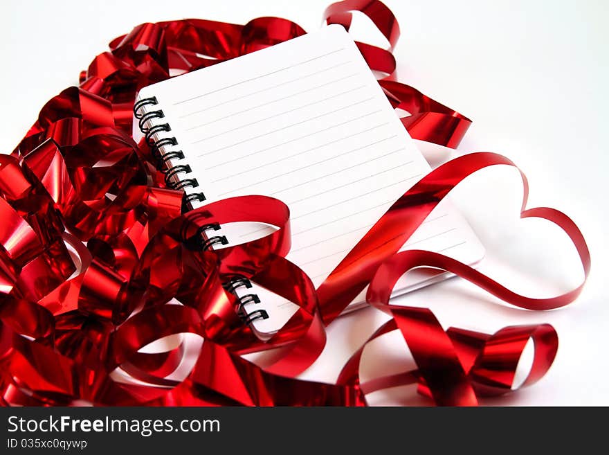 Valentine background with writing-pad and shiny red ribbons in the shape of heart. Valentine background with writing-pad and shiny red ribbons in the shape of heart