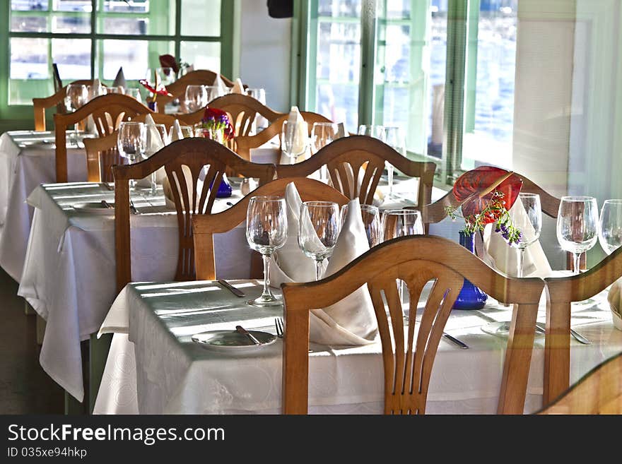 Table is set in a restaurant with glasses, flowers and tablecloth