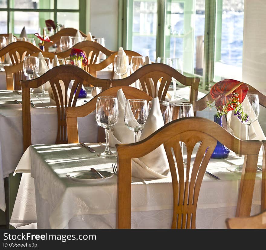 Table is set in a restaurant with glasses, flowers and tablecloth