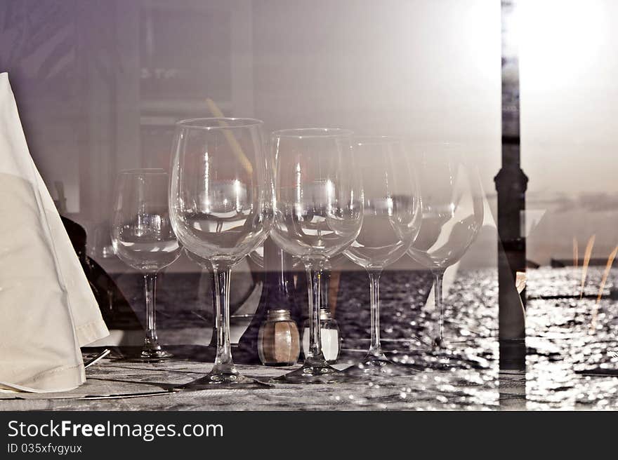 Table is set in a restaurant with glasses, flowers and tablecloth