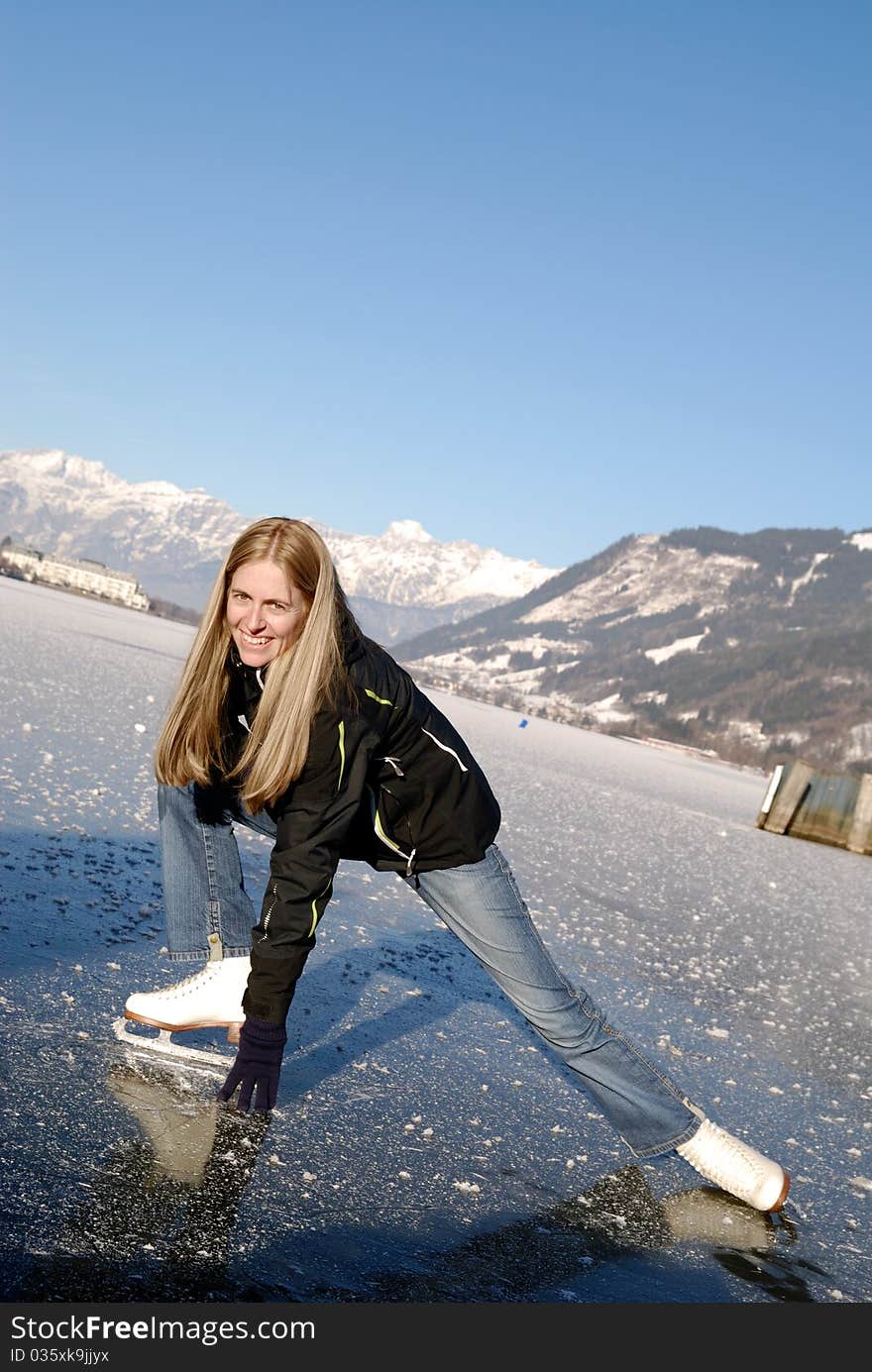 Young woman figure skating at frozen lake of zell am see in austria