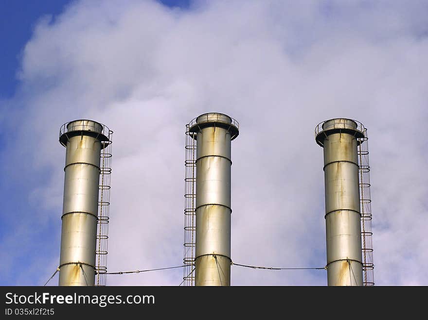 Inactive power plant towers on cloudy summer day.