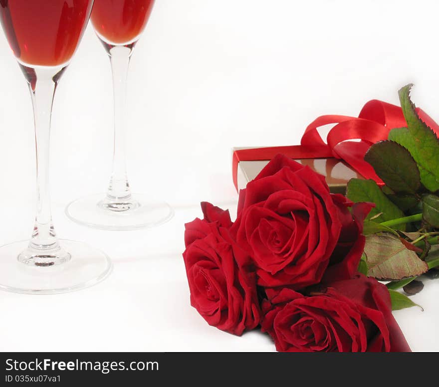 A bouquet of red roses with gift box and wine glass on white background. A bouquet of red roses with gift box and wine glass on white background