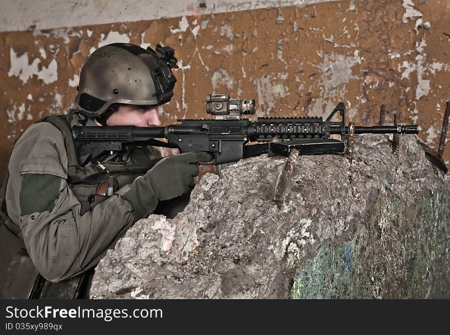 Young soldier in ruined building behind obstacle, aiming. air soft gun player. Young soldier in ruined building behind obstacle, aiming. air soft gun player.