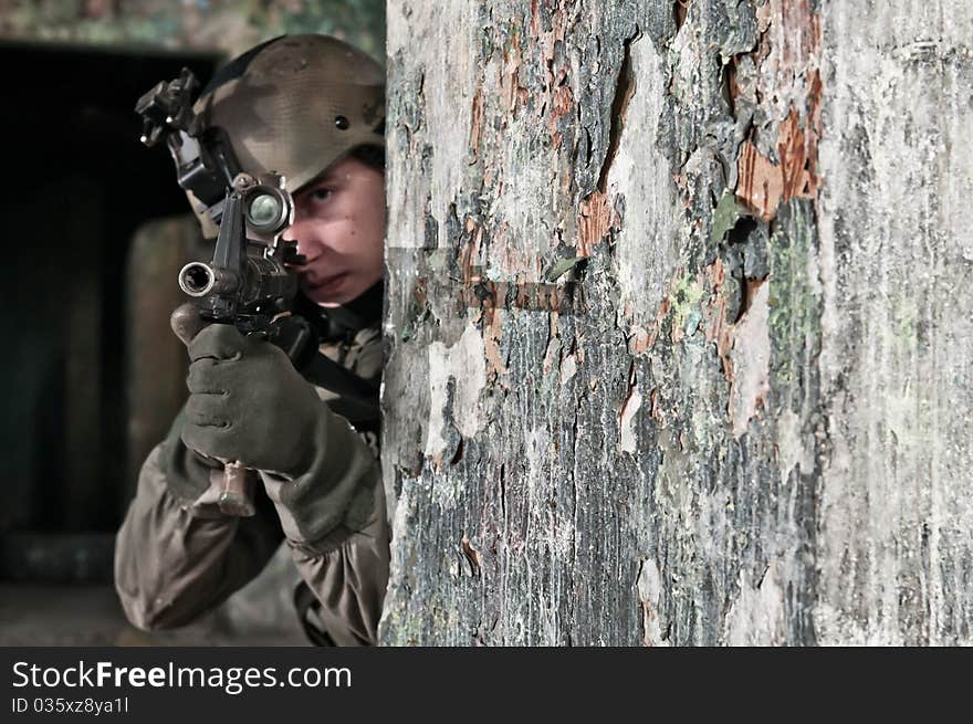 Young soldier in ruined building behind obstacle, aiming. air soft gun player. Young soldier in ruined building behind obstacle, aiming. air soft gun player.