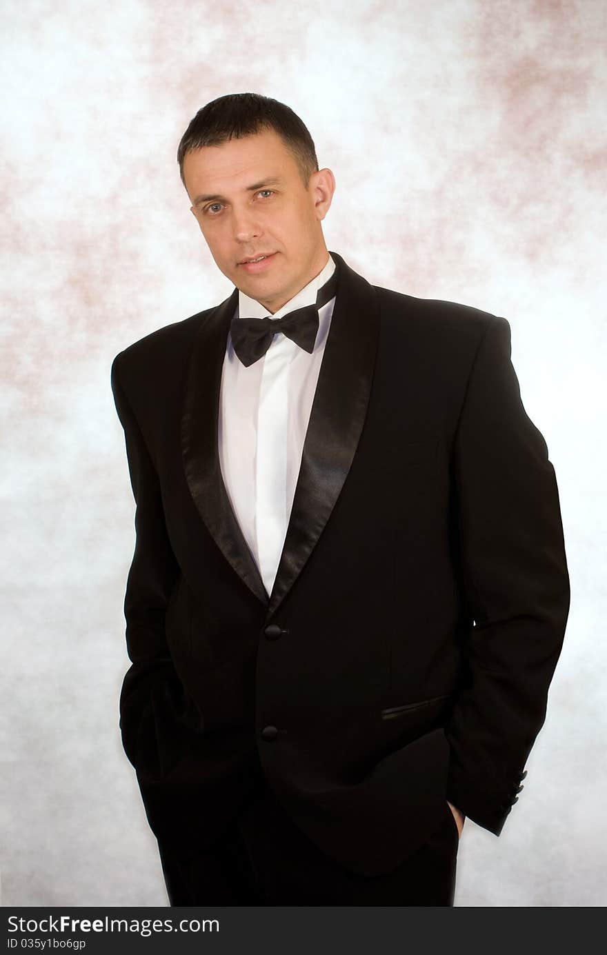 Portrait the man in a classical tuxedo on an abstract background