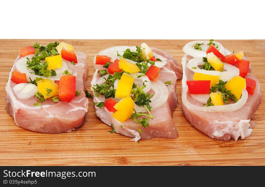 Raw pork chop with vegetables on a cutting board