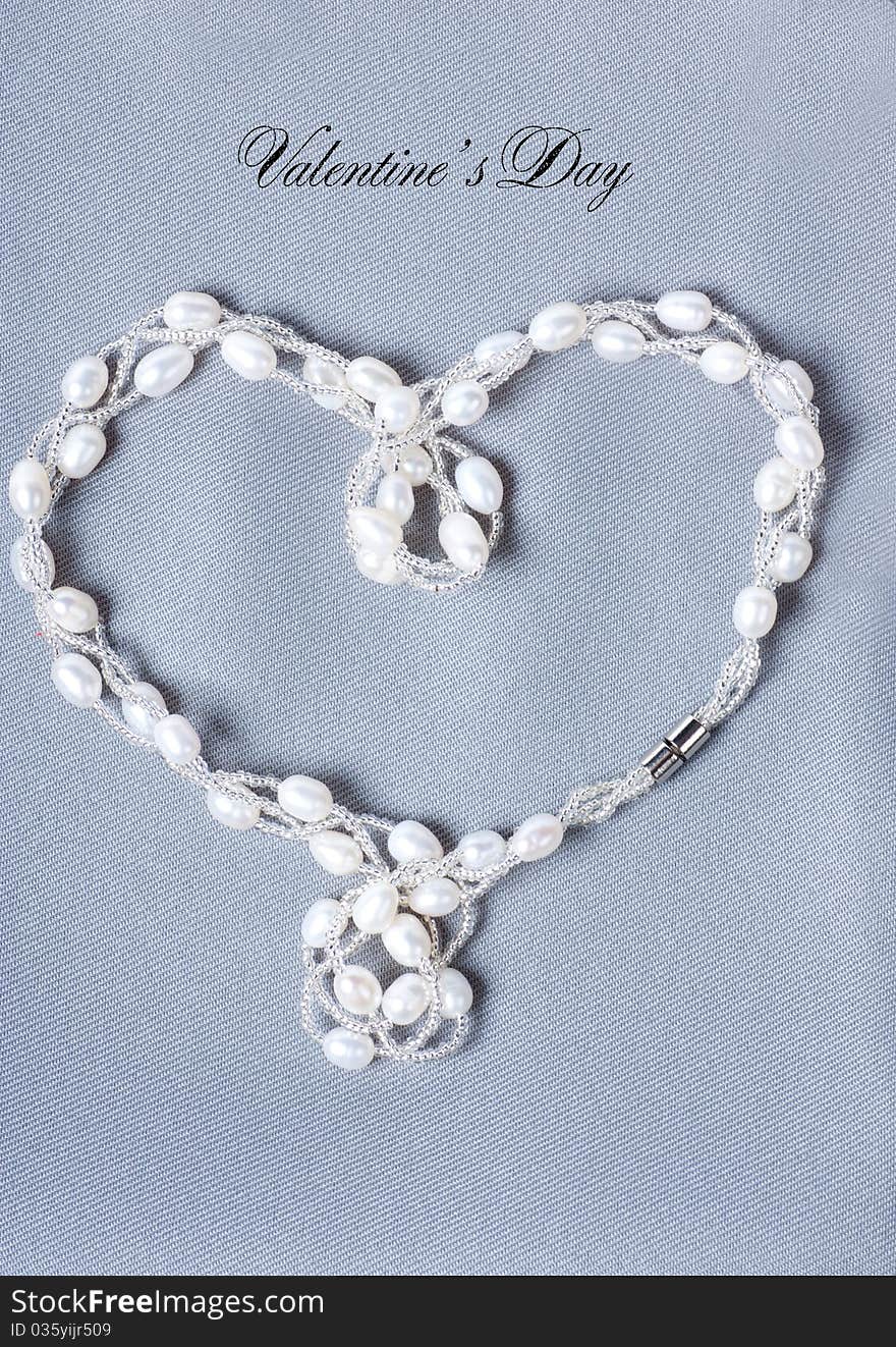 Heart-shaped string with pearls on a gray cloth. Heart-shaped string with pearls on a gray cloth