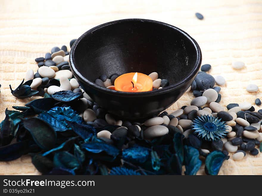 Orange candle in a black bowl and a blue potpourri. Orange candle in a black bowl and a blue potpourri