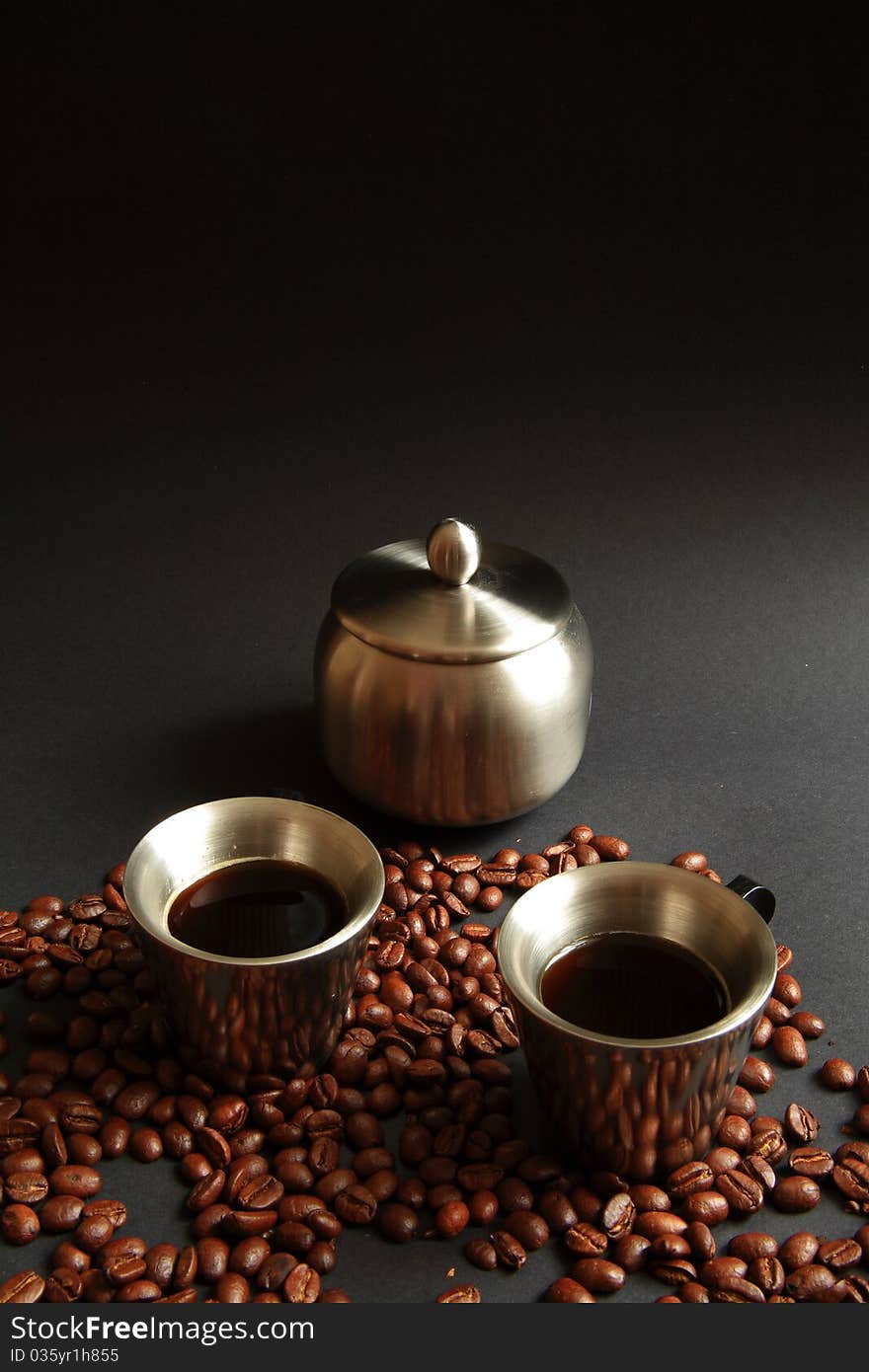 Two coffe in metal cup with sugar bowl and roasted beans on black background. Two coffe in metal cup with sugar bowl and roasted beans on black background.