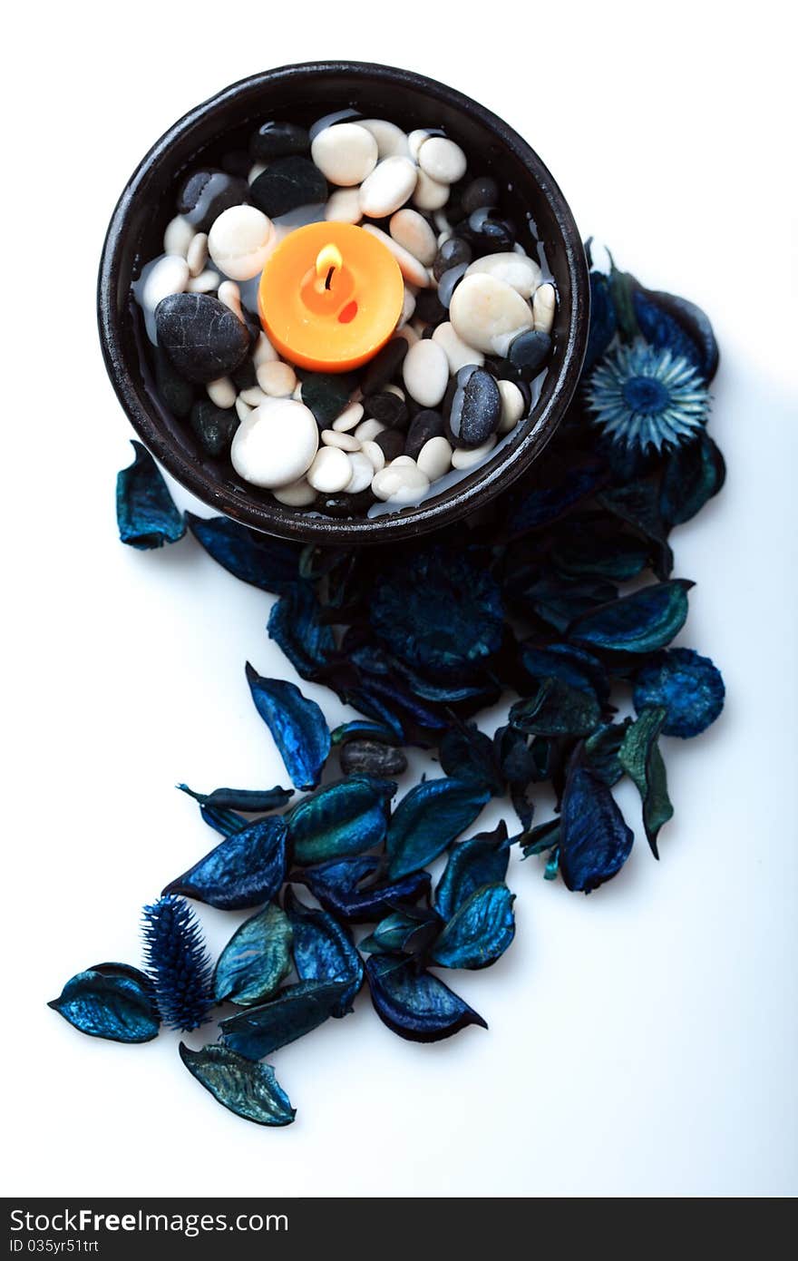 Orange candle in a black bowl and blue potpourri. Orange candle in a black bowl and blue potpourri