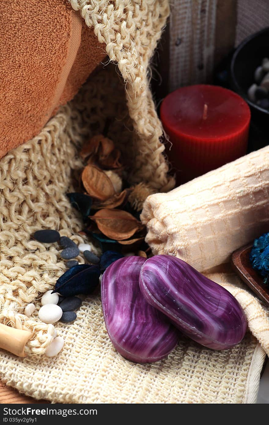 Two violet soaps and the red candle placed among towels. Two violet soaps and the red candle placed among towels