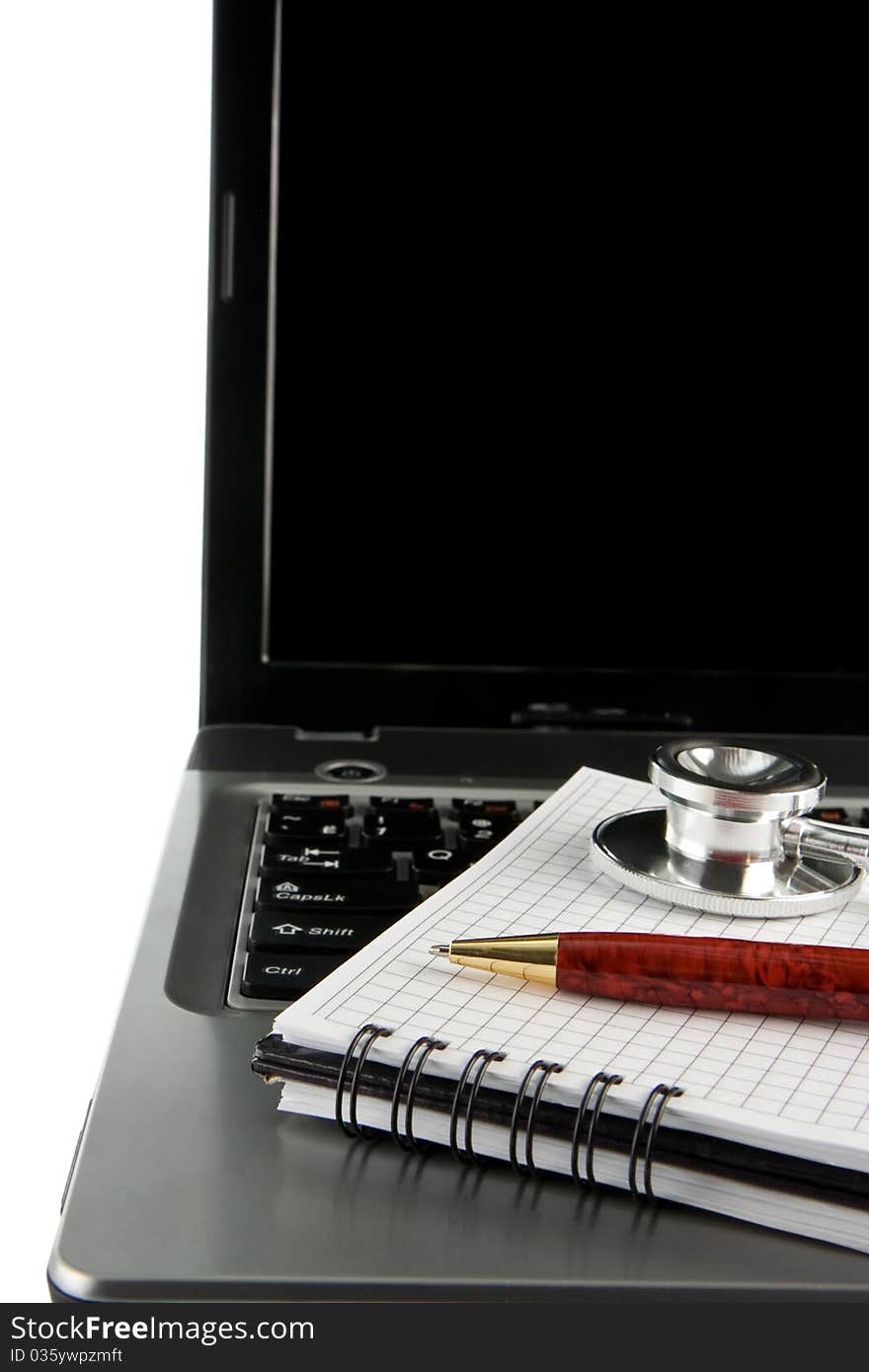 Stethoscope and pen at notebook laptop isolated on white background