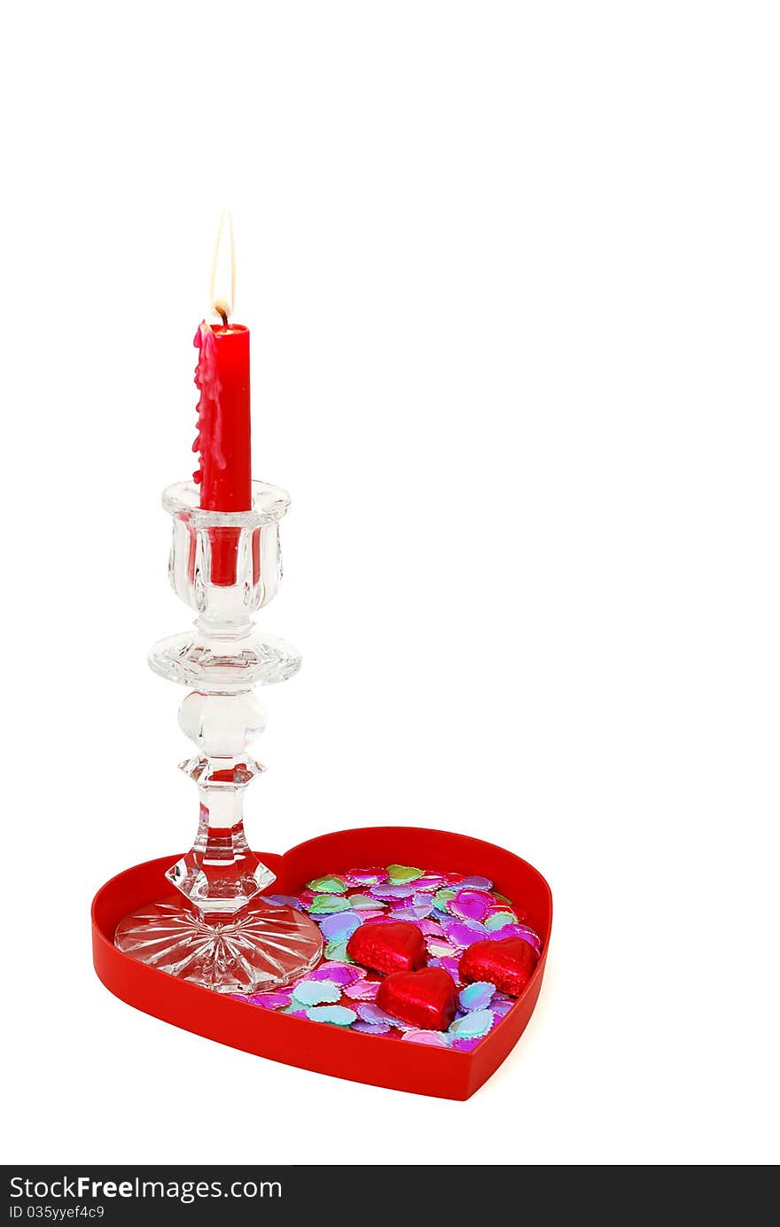 Red candle in glass candlestick on heart shaped tray with candies and sparkles. Red candle in glass candlestick on heart shaped tray with candies and sparkles