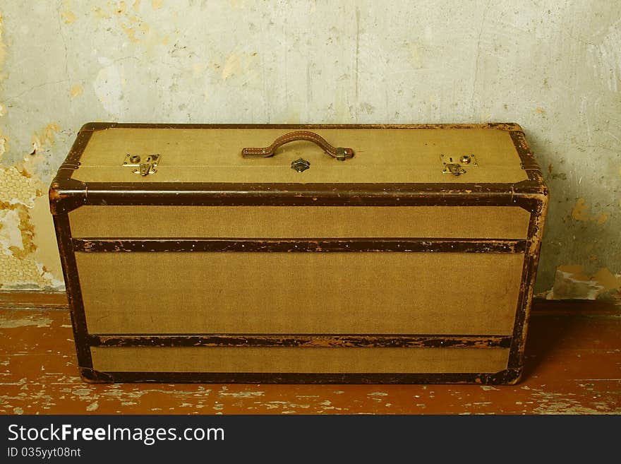 Old-fashioned suitcase standing on the old wooden floor