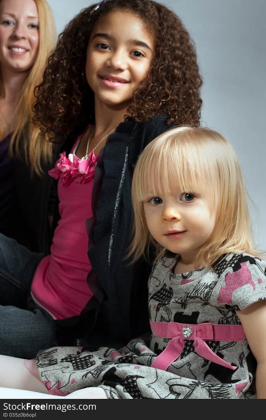 Young girl in front with her older sister behind and their mother in the back. Generational as well as a contrast between the different skin tones. Young girl in front with her older sister behind and their mother in the back. Generational as well as a contrast between the different skin tones.