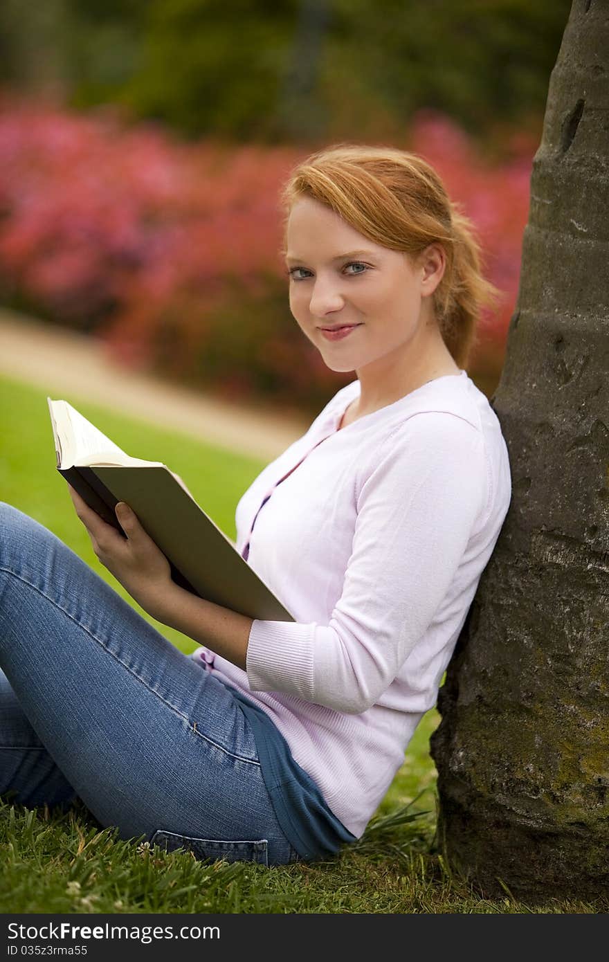 Young woman sitting outside reading. Young woman sitting outside reading