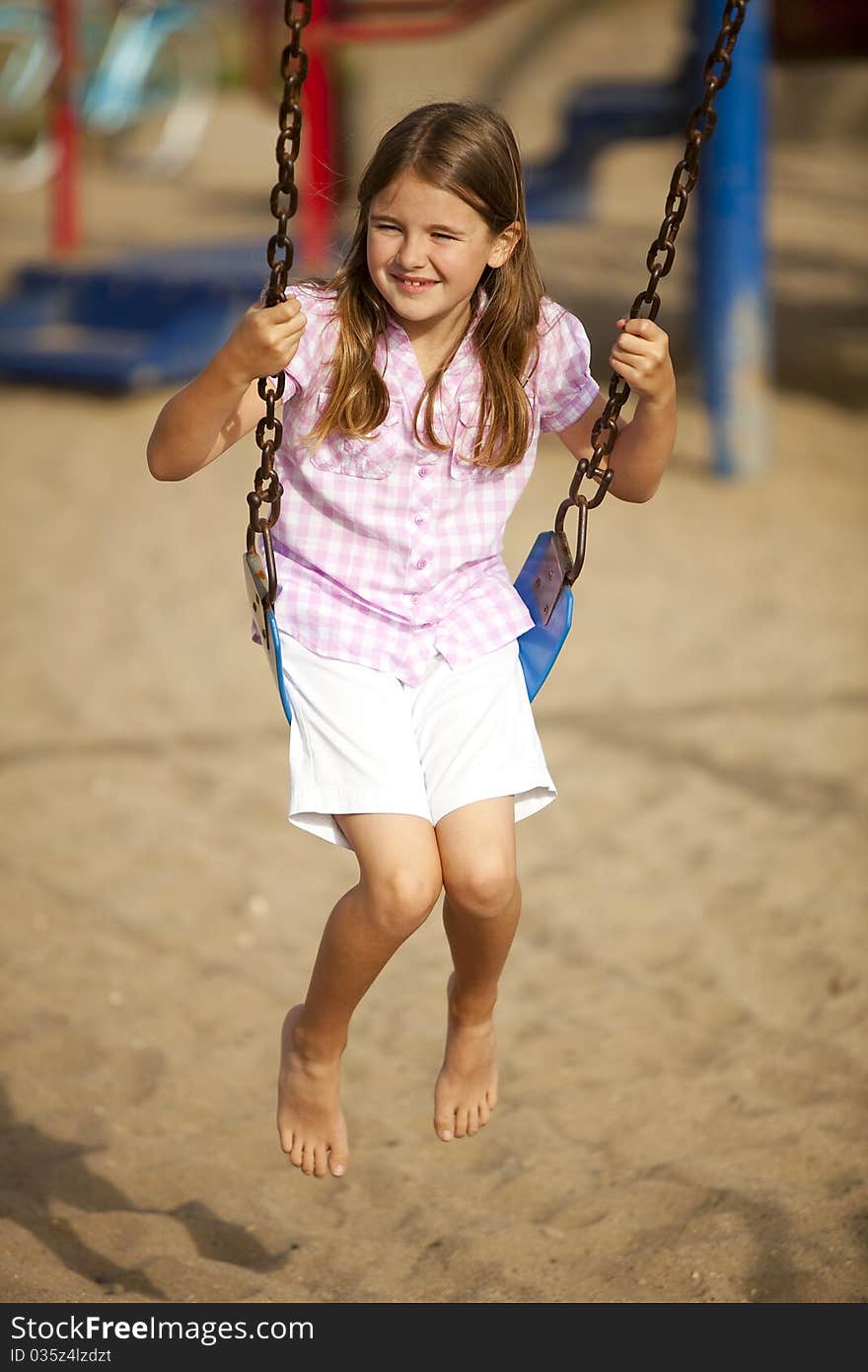 Little girl playing at a park swinging. Little girl playing at a park swinging