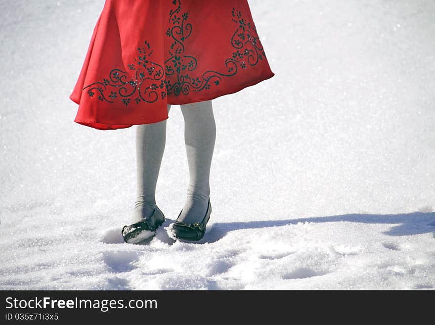 Young girl standing in the snow in a bright red dress. Young girl standing in the snow in a bright red dress.