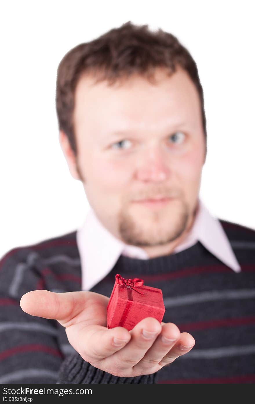 Young man holding valentine gift in his hand. He is giving it somebody. Isolated on white.