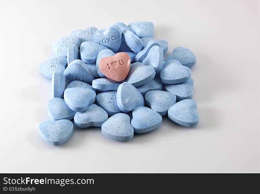 Close up of a small pile of blue Valentine's Day candy hearts with one pink I heart U heart in the middle. Close up of a small pile of blue Valentine's Day candy hearts with one pink I heart U heart in the middle