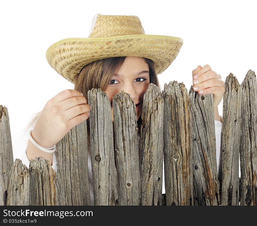 A beautiful young teen in a straw hat peeking over a rustic picket fence. Isolated on white. A beautiful young teen in a straw hat peeking over a rustic picket fence. Isolated on white.