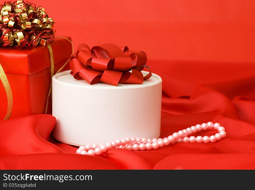 Box with a gift on a red fabric still life