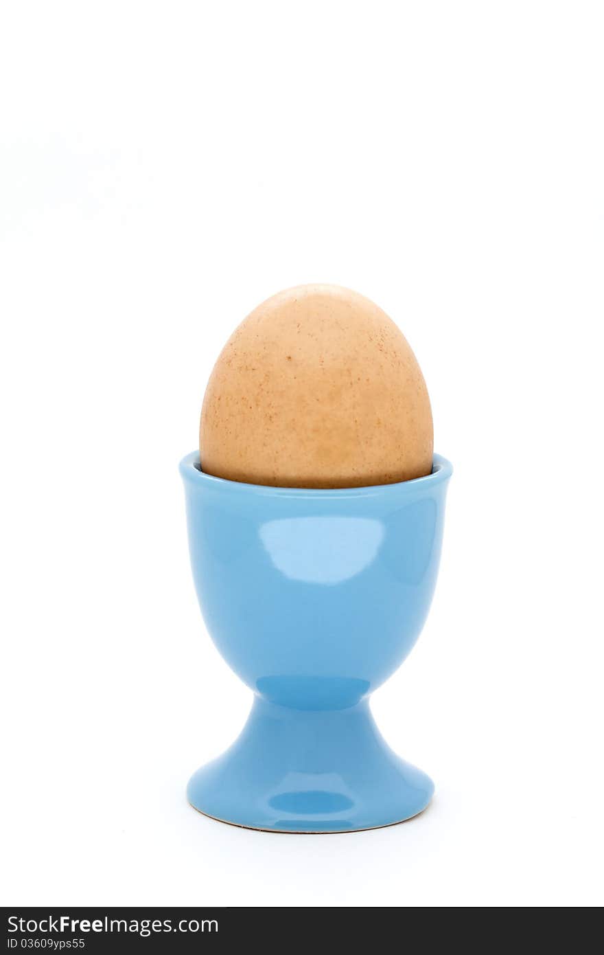 Egg in blue egg cup on white background. Egg in blue egg cup on white background