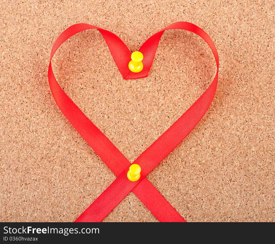 Red heart shaped ribbon pinned to cork board